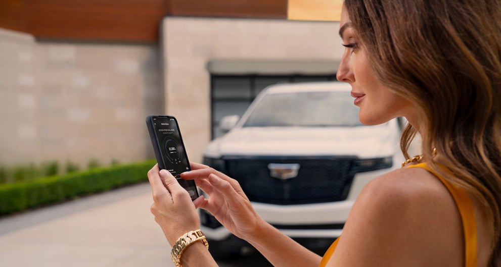 lady checking her mobile with a Cadillac vehicle background | Dutton Cadillac in RIVERSIDE CA