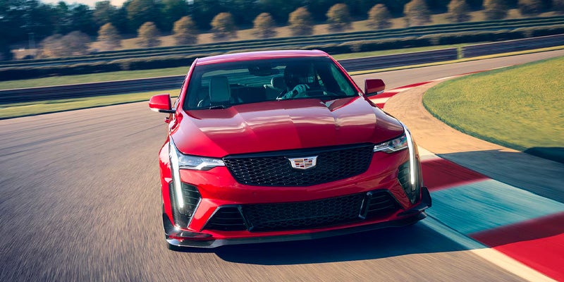 Front view of a red Cadillac CT4-V Blackwing sports sedan driving quickly on a racetrack.