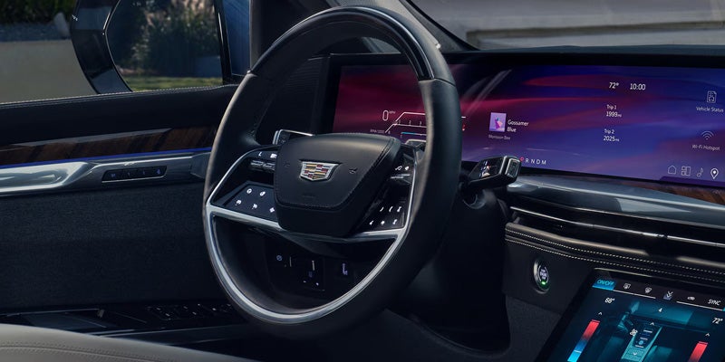 Interior shot of a car's dashboard, showing a large digital display, steering wheel, and wood trim.